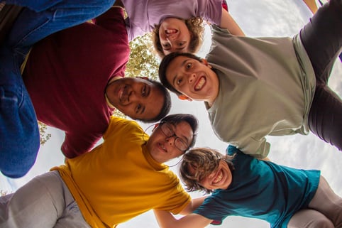 A group of smiling friends huddled together, looking down into the camera.